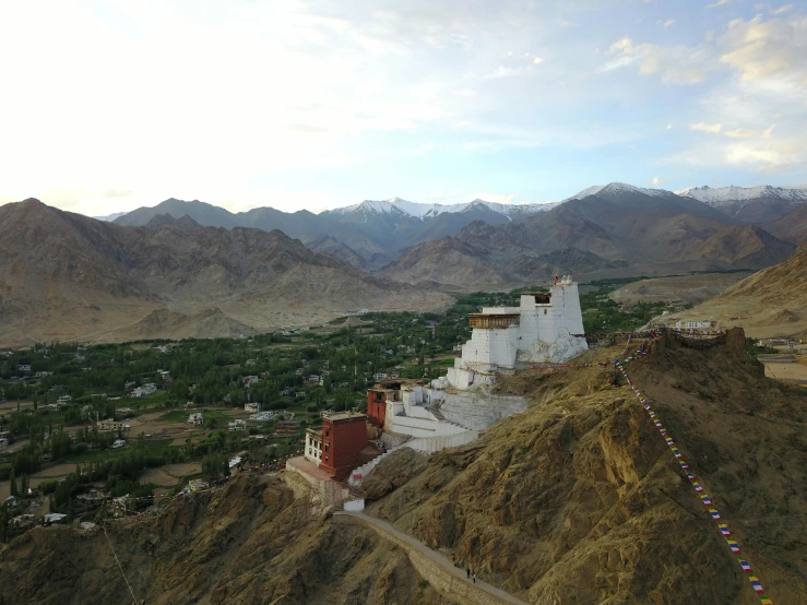 a hill with some houses in it surrounded by mountains