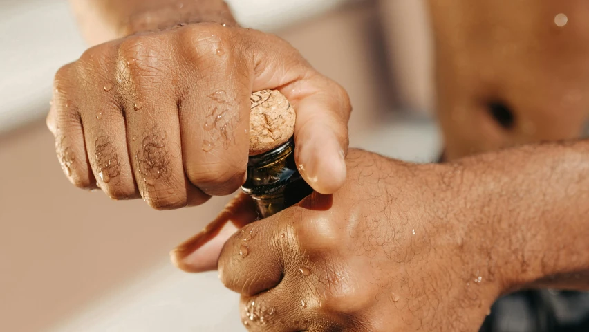 a man holding a bottle with sand on it