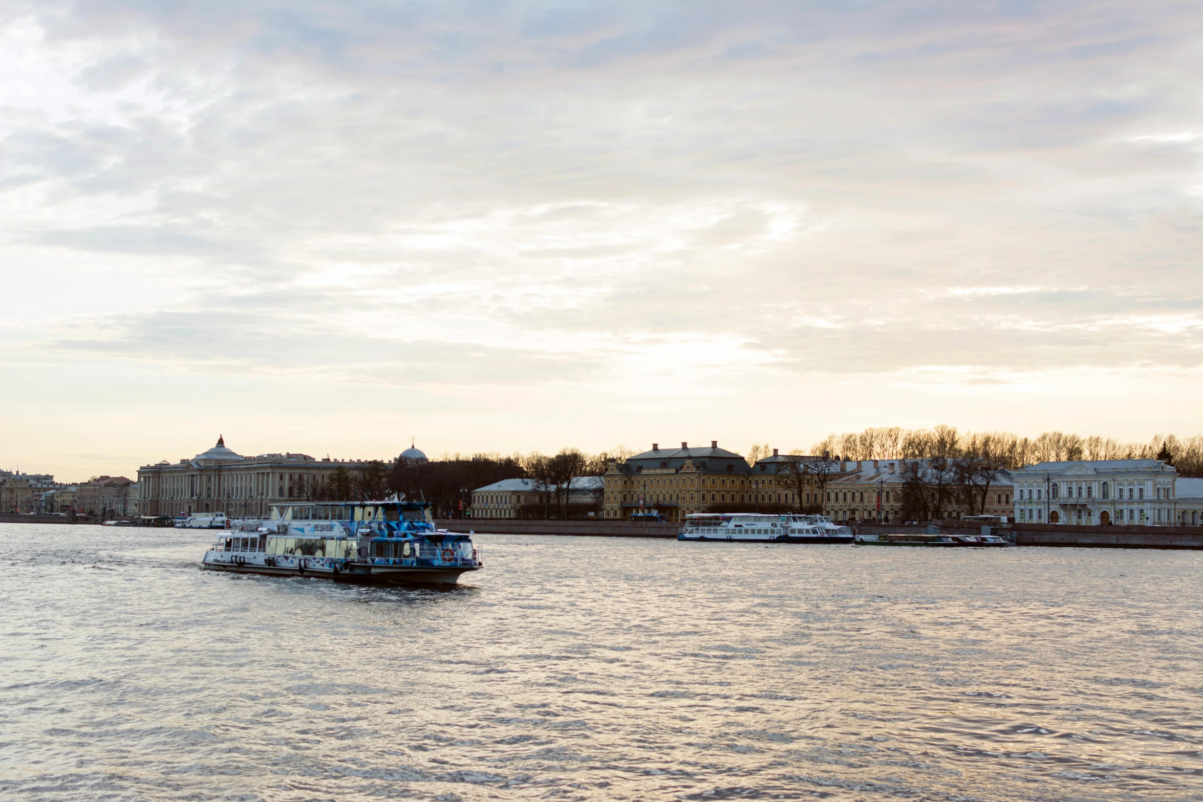 a boat sailing down the river on a cloudy day