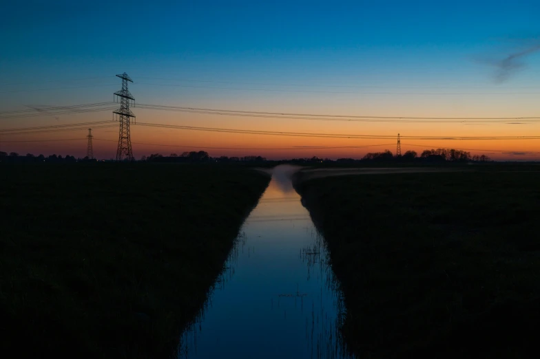 a sunset is reflecting in a ditch and telephone wires