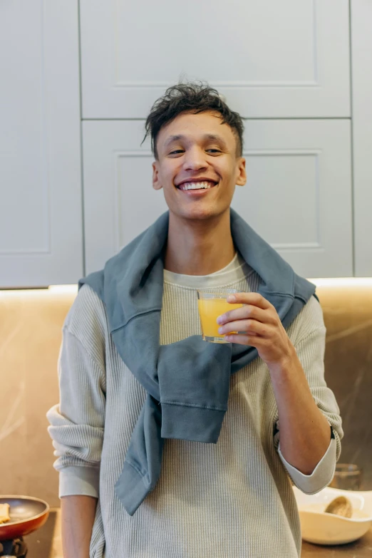 a man holding a yellow cup and wearing a jacket