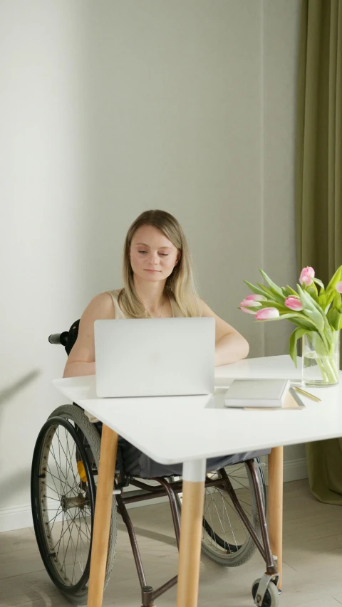 a girl is in a wheelchair working on a computer