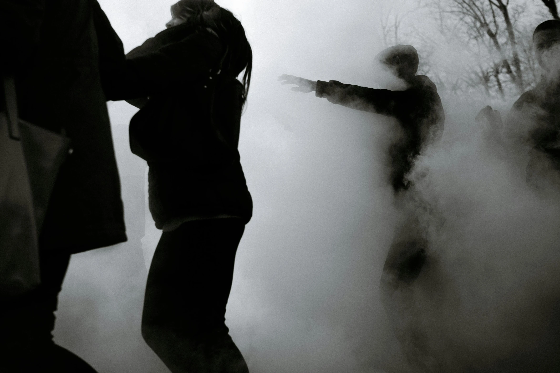 people standing in smoke and another person pointing the way