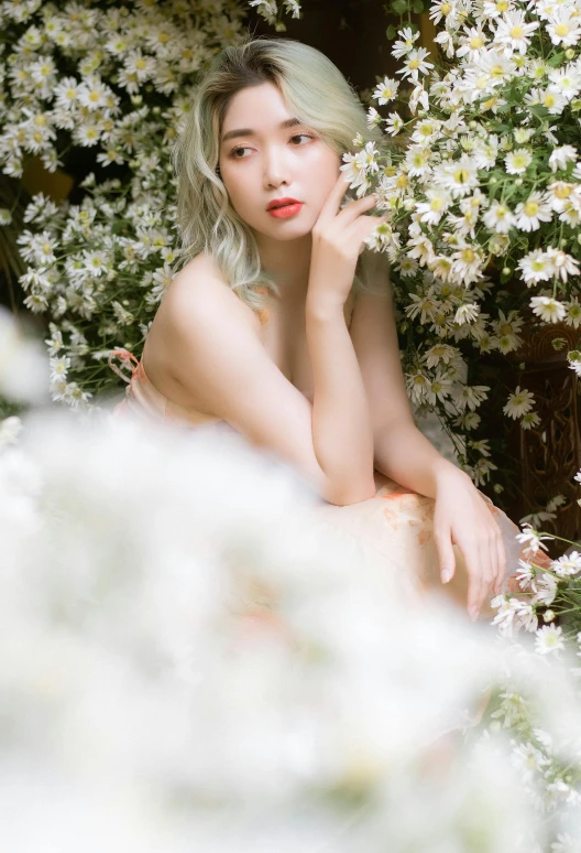 a woman sitting in front of white flowers