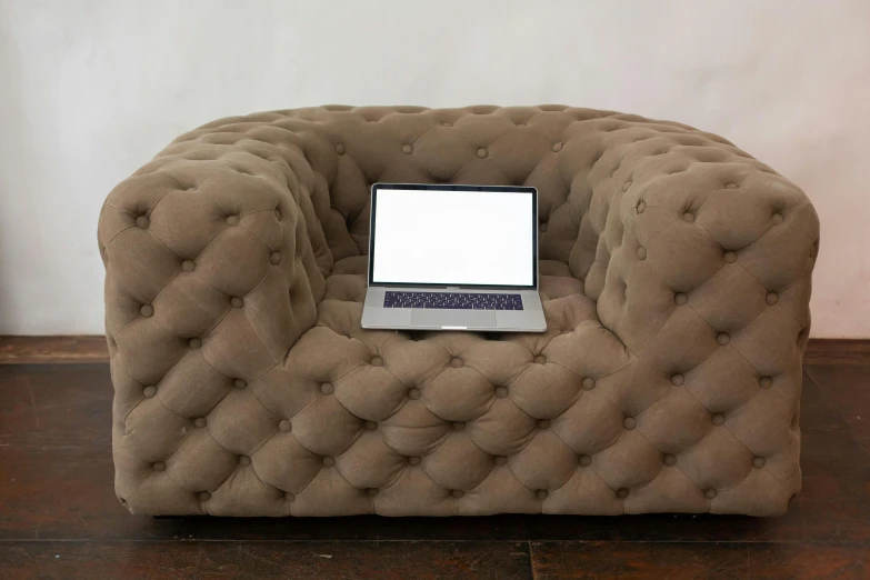 a laptop on a modern designed plush chair