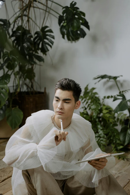 man in white shirt sitting down holding a cigarette