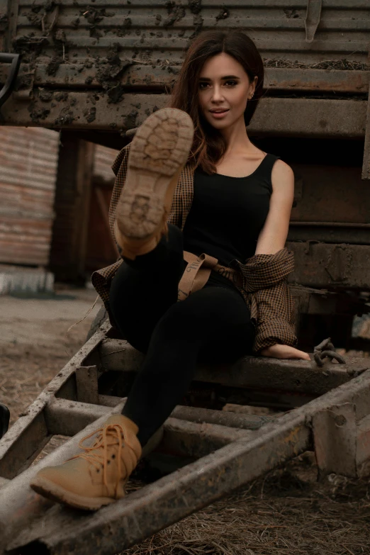 a woman in a black top a wooden cart and brown boots