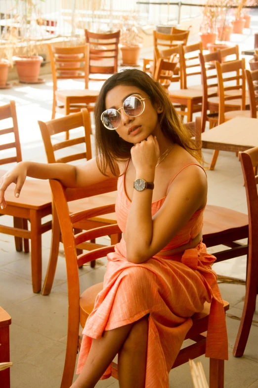 a young woman sits in a wooden chair with her hand on the side