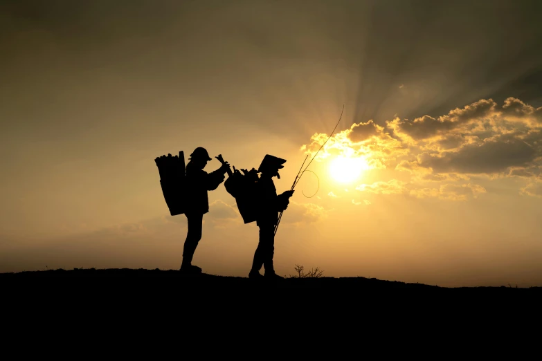 two people in silhouette with a kite and backpack