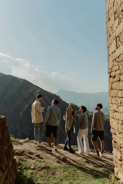 a group of people standing on top of a grass covered hillside