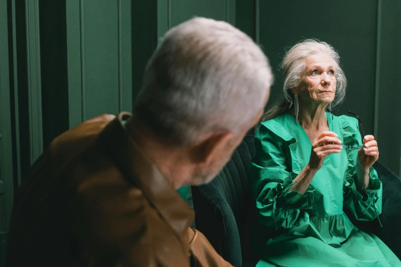 an older person in green sitting in a chair