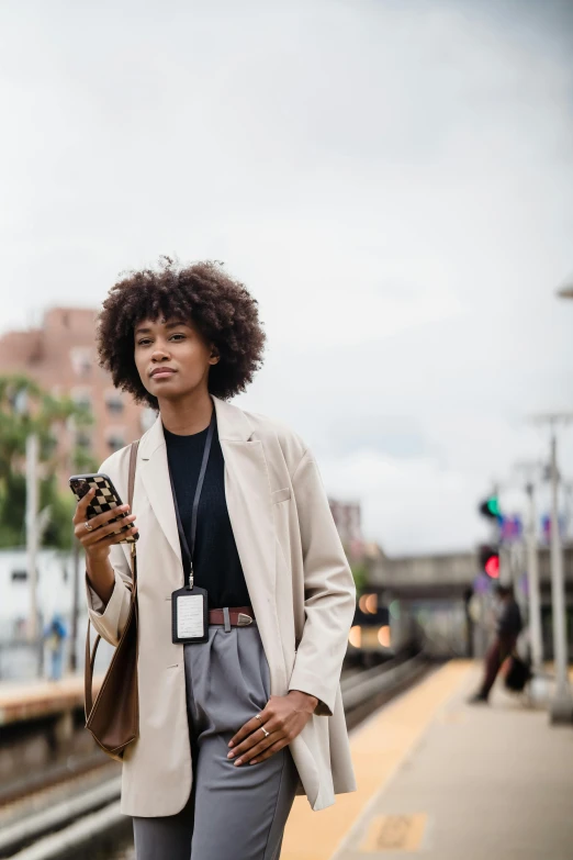 a person with curly hair stands next to a train platform