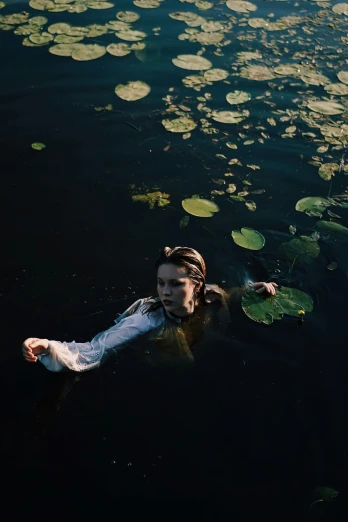 the woman is swimming on the water with lily pads