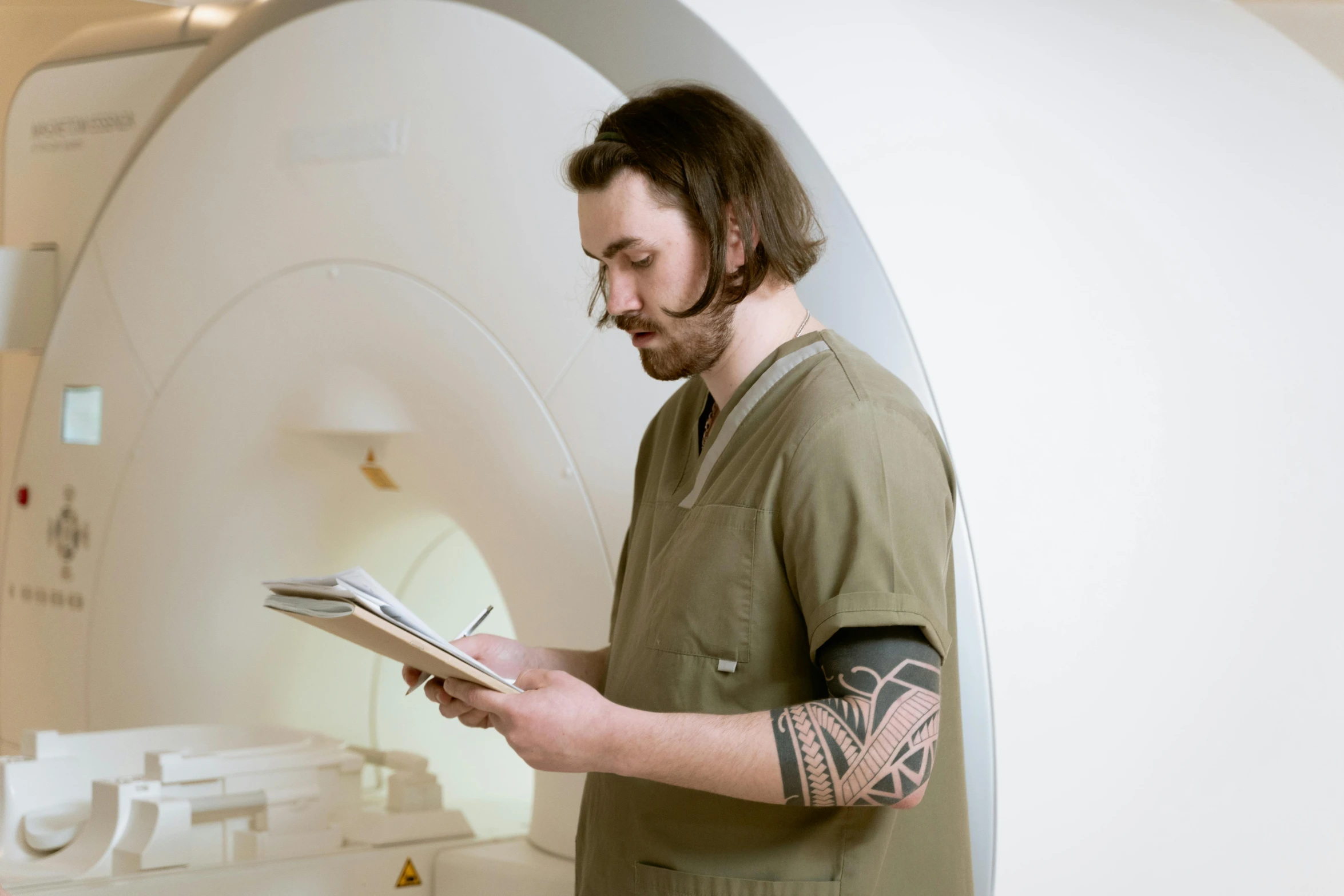 a man wearing tattoos looking at soing while holding a book