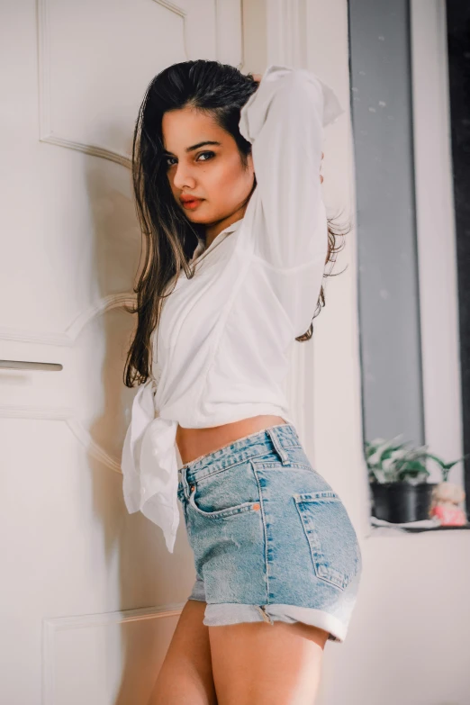 a beautiful young woman in shorts standing next to a door