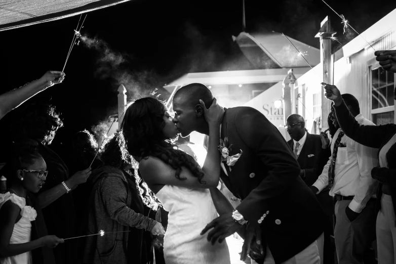 a man and woman kiss while surrounded by guests