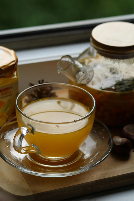 there is a glass cup filled with tea sitting on a glass table