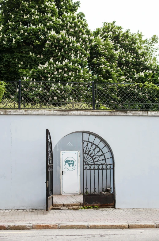 an iron gate between two buildings with a white wall
