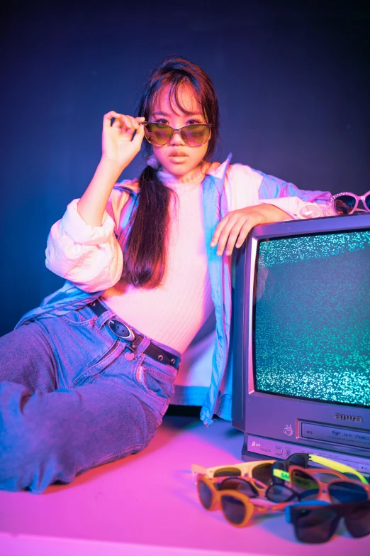 a woman sitting next to a tv holding a cell phone and smoking