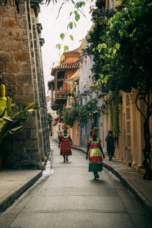 two woman in mexican garb walk down a narrow street