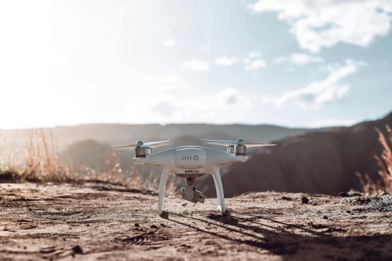 a white unmanned flying over a dusty road