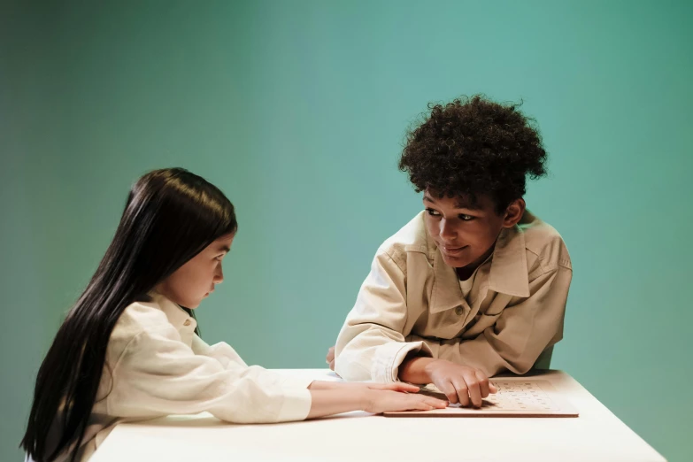 a girl is looking at a boy sitting at a table