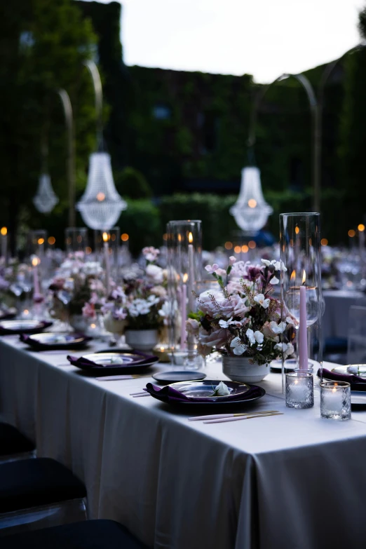 tables lined up with white cloths and tall vases of flowers