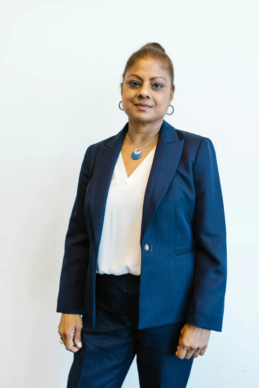 woman with glasses standing in front of a white wall