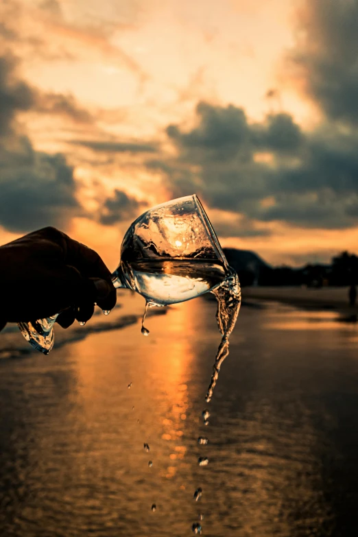 a person is holding a glass of water in the sky