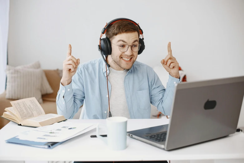 a man at a table in front of a laptop and a book