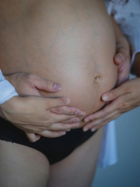 a pregnant woman is holding her hands over her belly