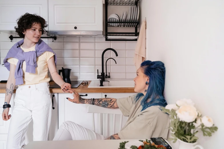 a woman in a kitchen with a blue hair talking to a man in a white shirt