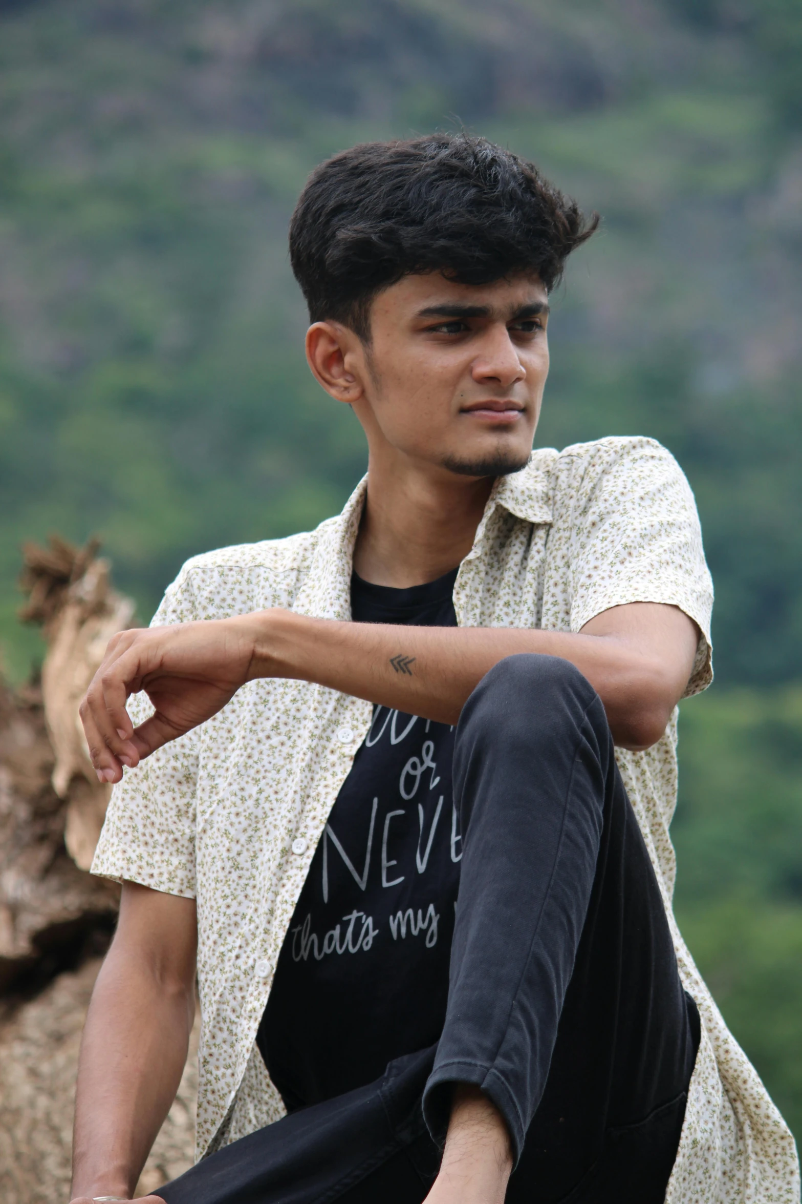 a young man sitting on a tree stump