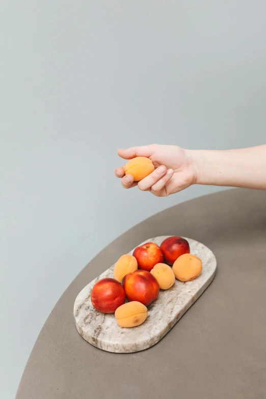 a person reaching for apples on a piece of fruit