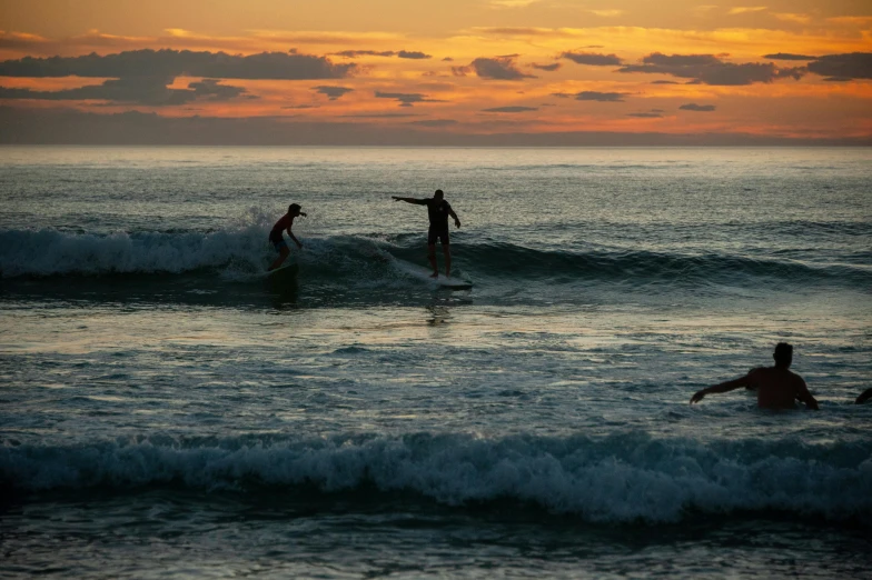 three people riding surfboards on top of waves in the ocean