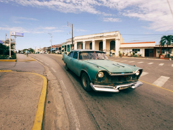 an old classic car driving down the road