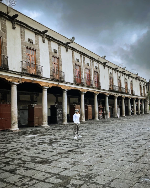 there is a man that is walking in front of some buildings