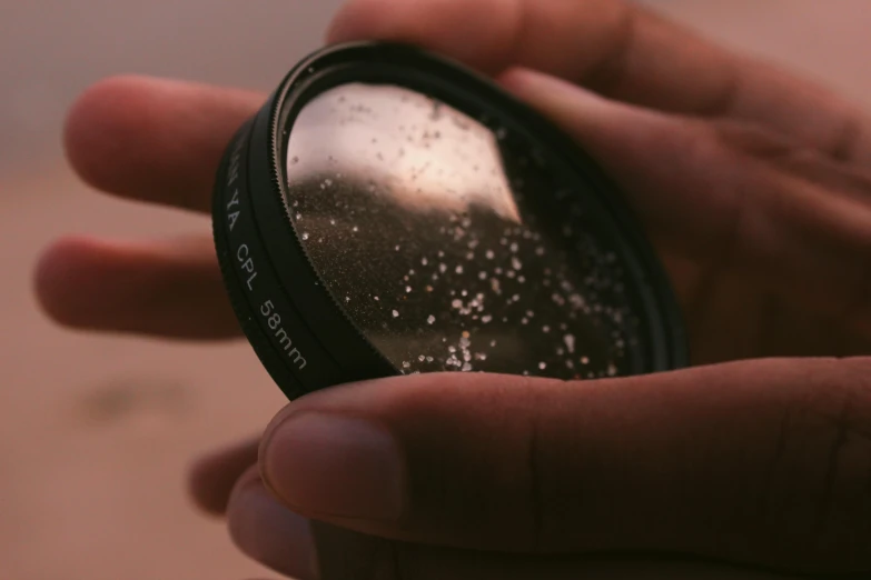 a hand that is holding a lens with some white stuff on it