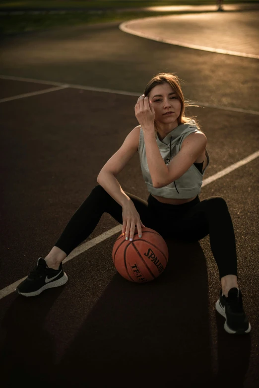 a girl sits on the basketball court holding her hand in the air