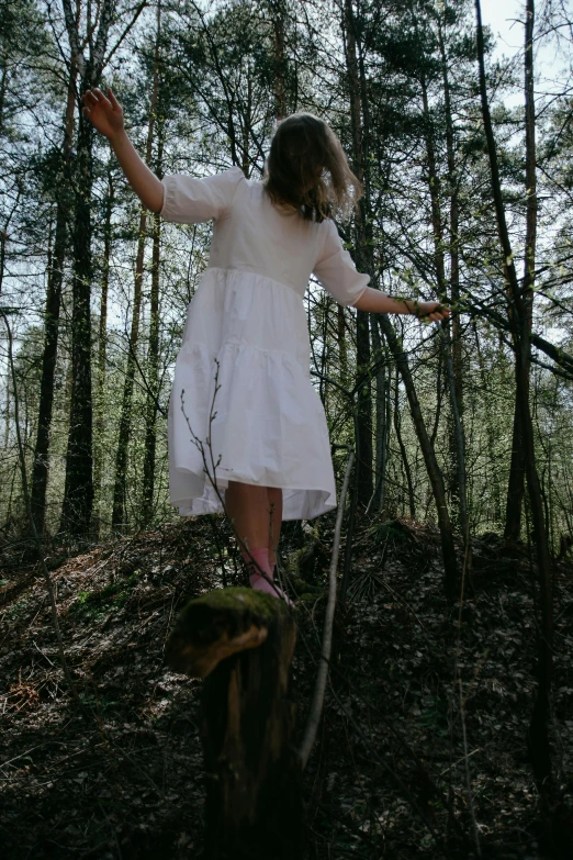 a girl in a white dress is walking on wood