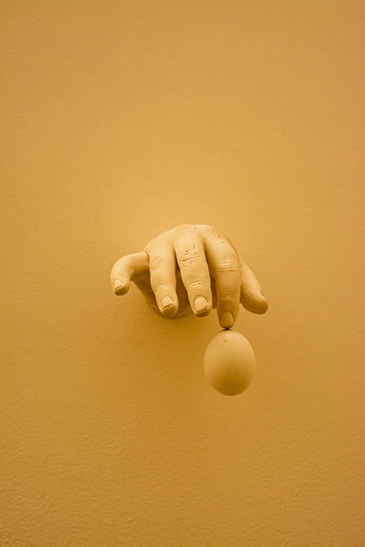 a hand holding a baseball on top of an object