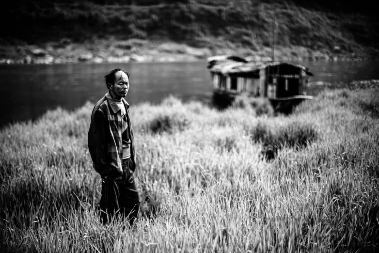 man standing in tall grass next to the river