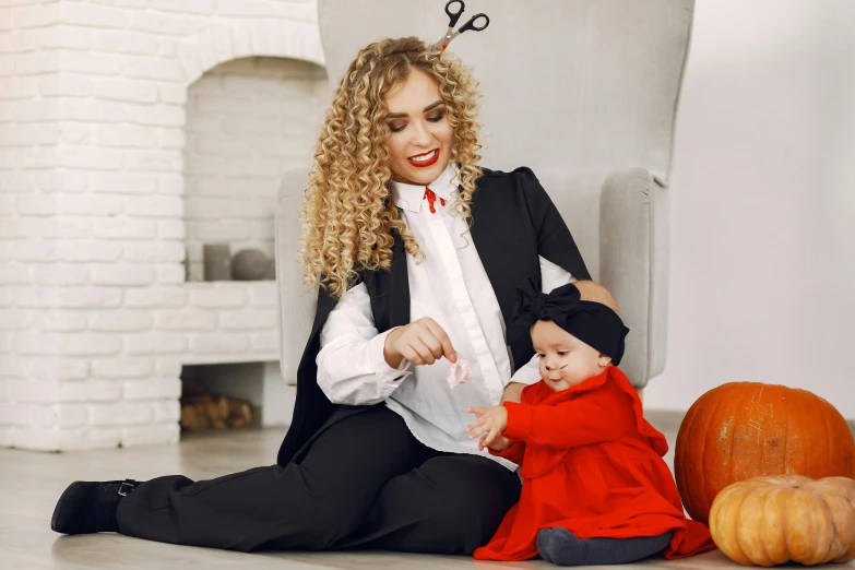 a woman is holding a child and posing with fake pumpkins