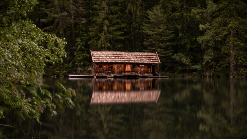 a cabin sitting next to a body of water surrounded by trees