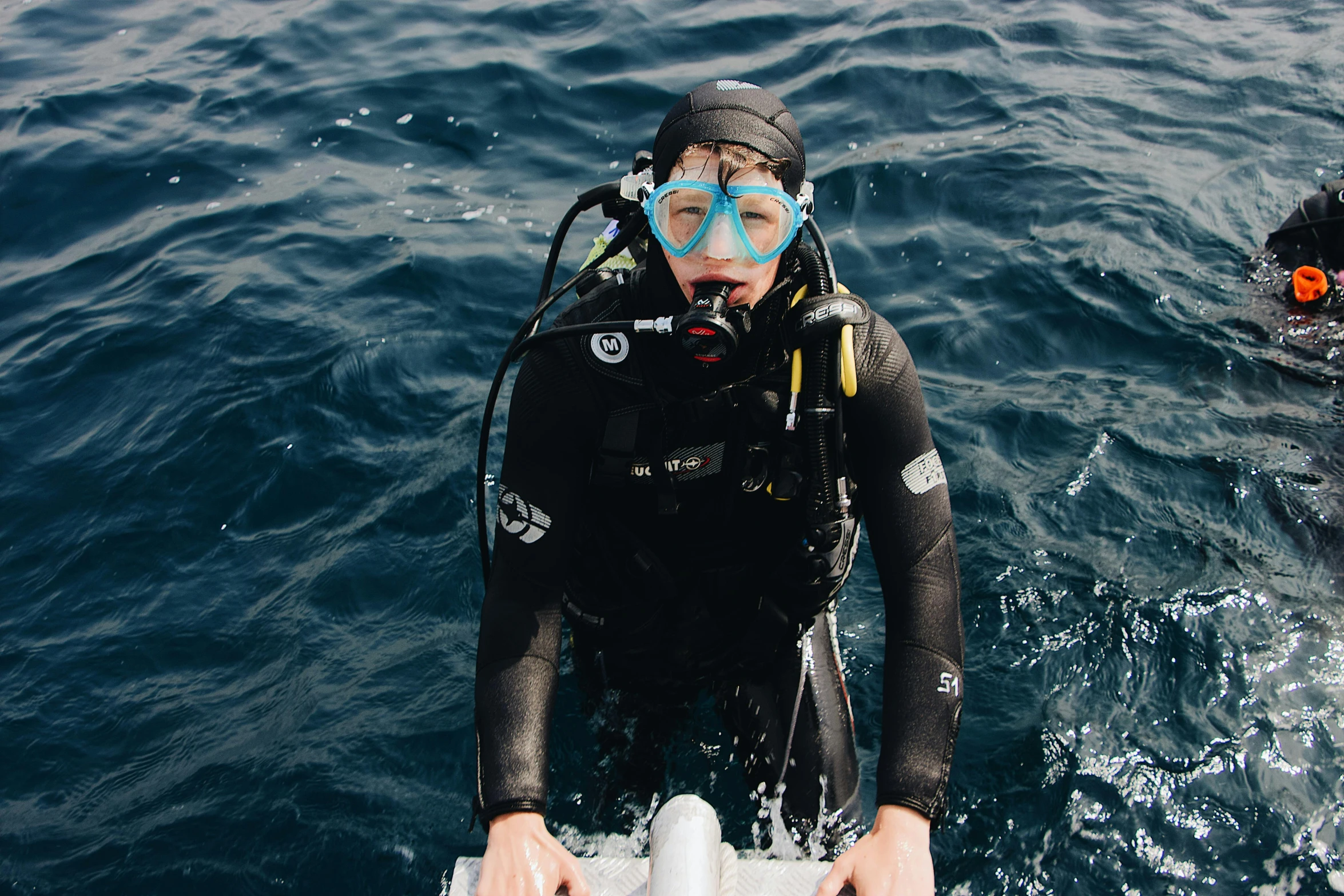 two people in scuba gear standing on small boats