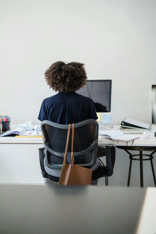 a woman sitting on a chair with her back turned towards a desk