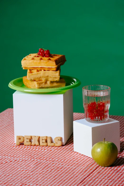 food sits on a table that includes waffles, apples and a glass