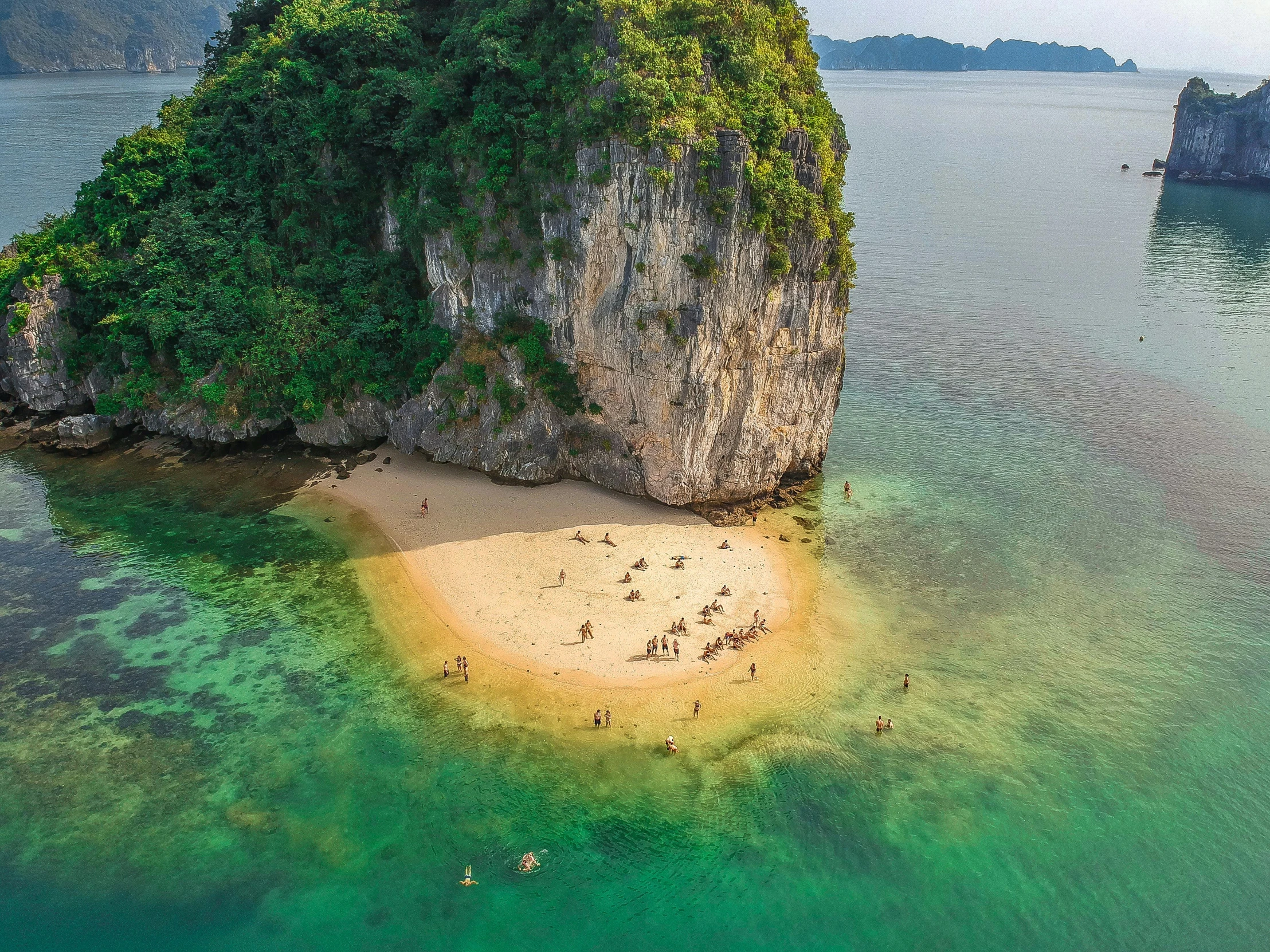 people floating in clear waters around an island