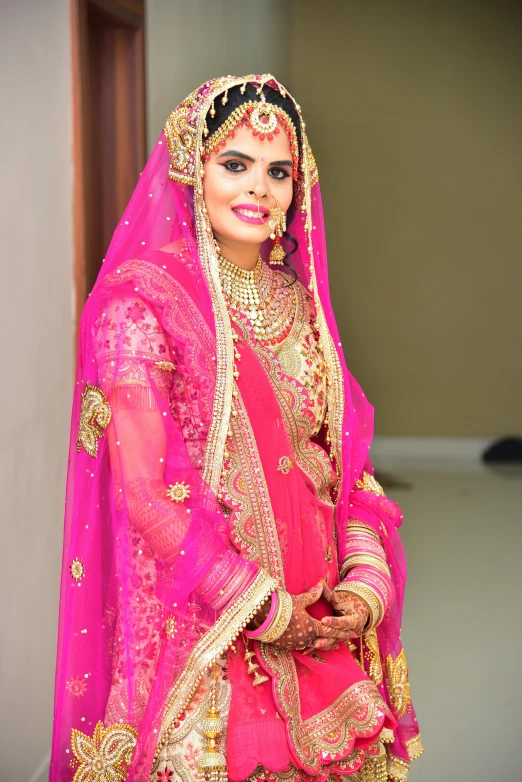 a bride is dressed in pink attire with gold trim