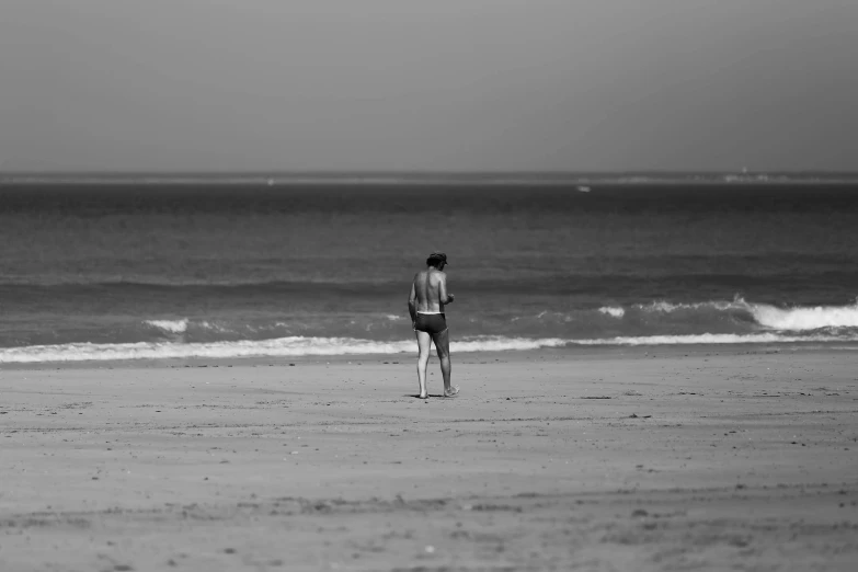 the man is walking down the beach on his surfboard